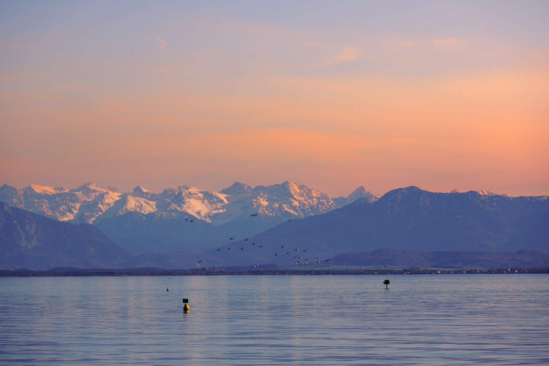 Bayerischer See mit schneebedeckten Alpen im Winterlicht